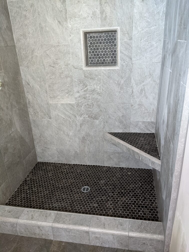 Porcelain tile shower with seat and pebble shower pan